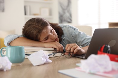 Photo of Tired student preparing for exam at table indoors