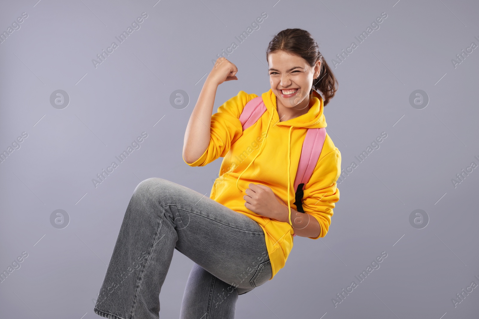 Student feeling happy about her good exam result on gray background Photo of Student feeling happy about her good exam result on gray background