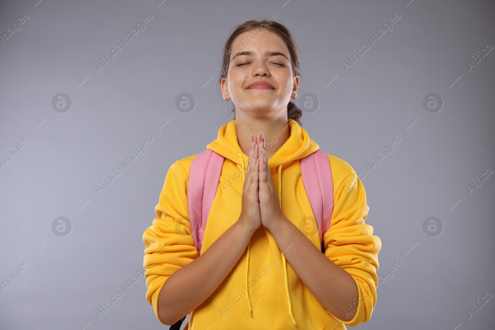 Student praying for good exam result on gray background Photo of Student praying for good exam result on gray background