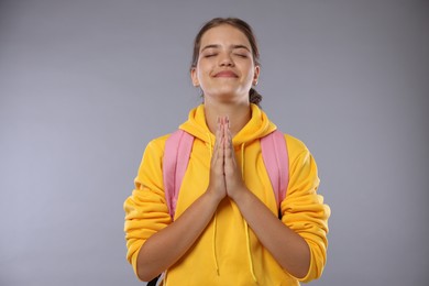 Photo of Student praying for good exam result on gray background