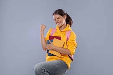 Photo of Student with notebooks feeling happy about her good exam result on gray background