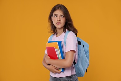 Photo of Student with notebooks worried about her exam result on orange background