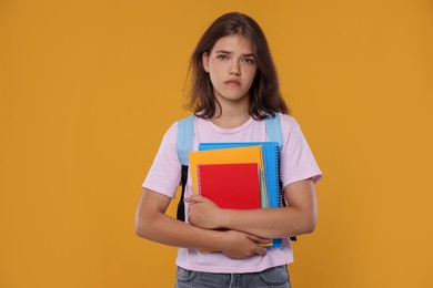 Photo of Student with notebooks worried about her exam result on orange background