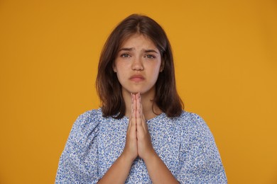 Photo of Student praying for good exam result on orange background