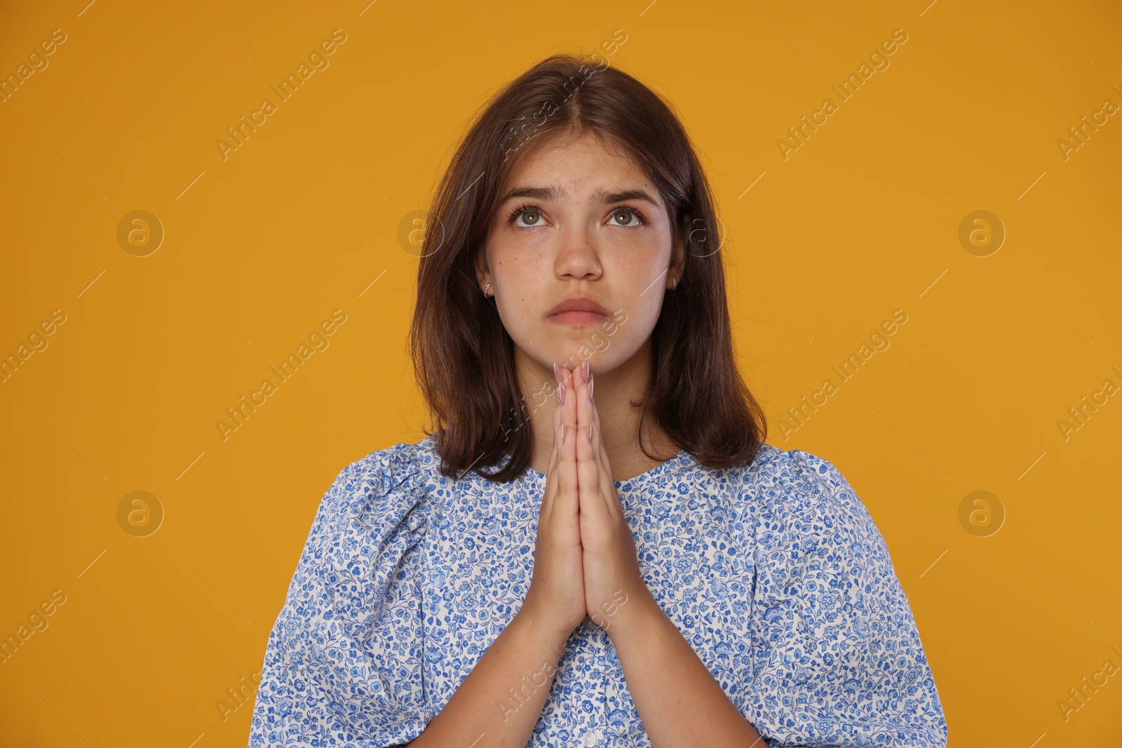 Student praying for good exam result on orange background Photo of Student praying for good exam result on orange background