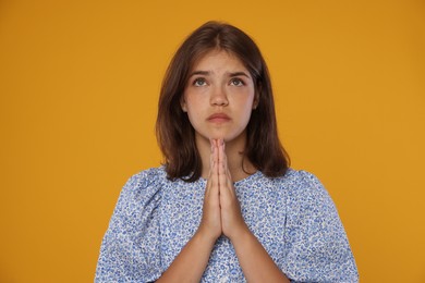 Photo of Student praying for good exam result on orange background
