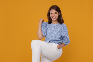 Photo of Student feeling happy about her good exam result on orange background