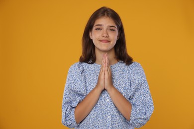 Photo of Student praying for good exam result on orange background
