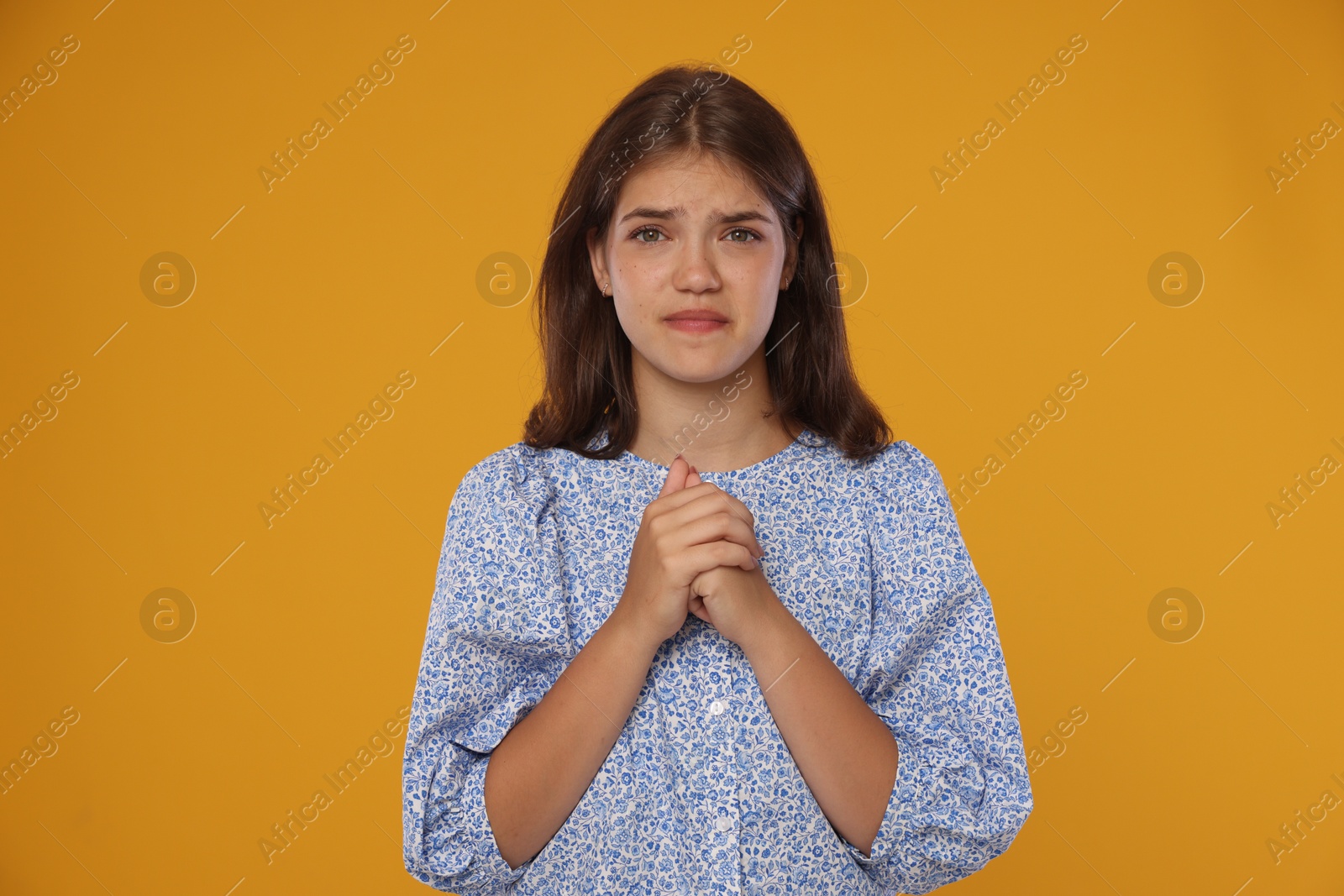 Student praying for good exam result on orange background Photo of Student praying for good exam result on orange background