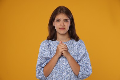 Photo of Student praying for good exam result on orange background