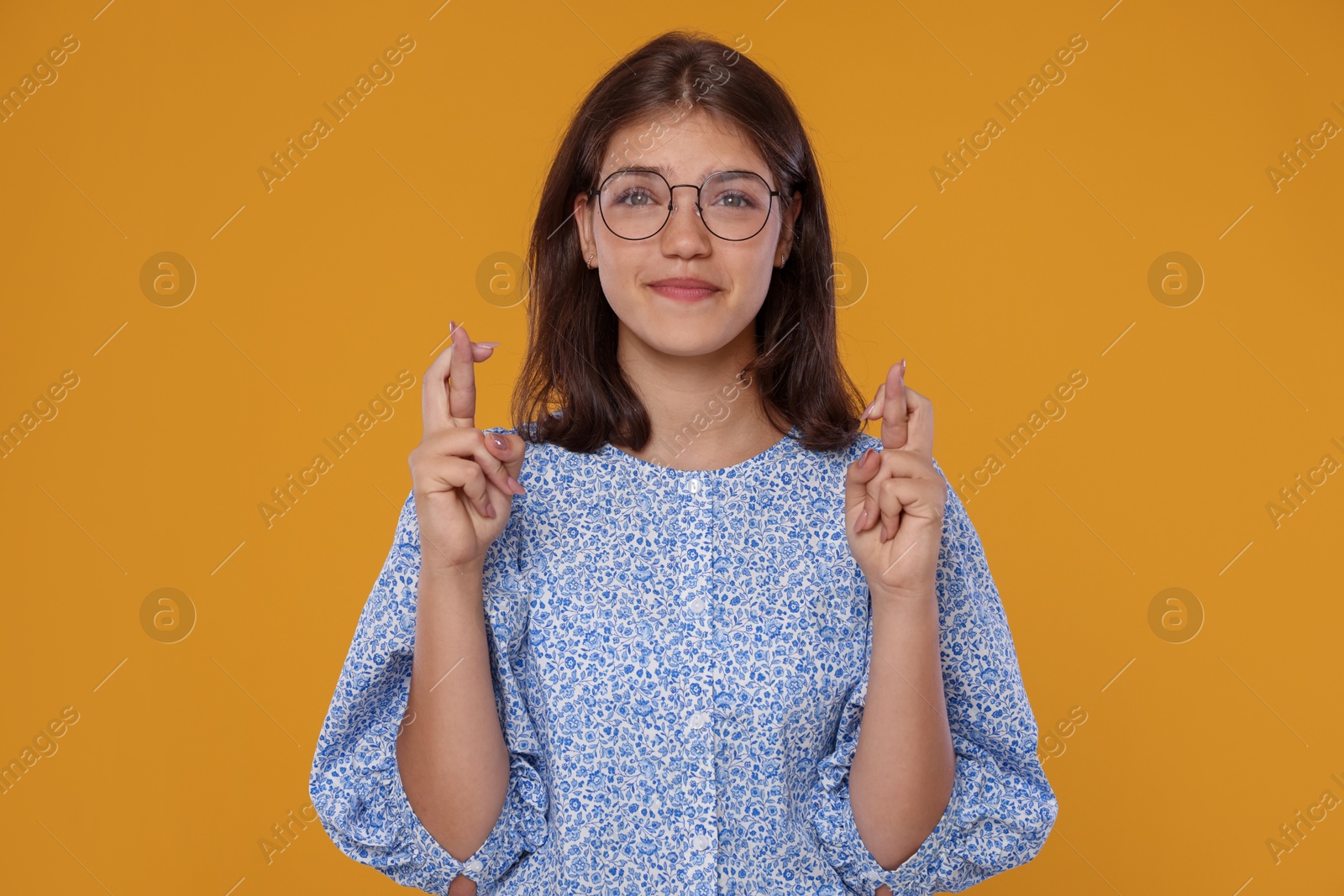 Student crossing fingers on orange background. Hope for good exam result Photo of Student crossing fingers on orange background. Hope for good exam result