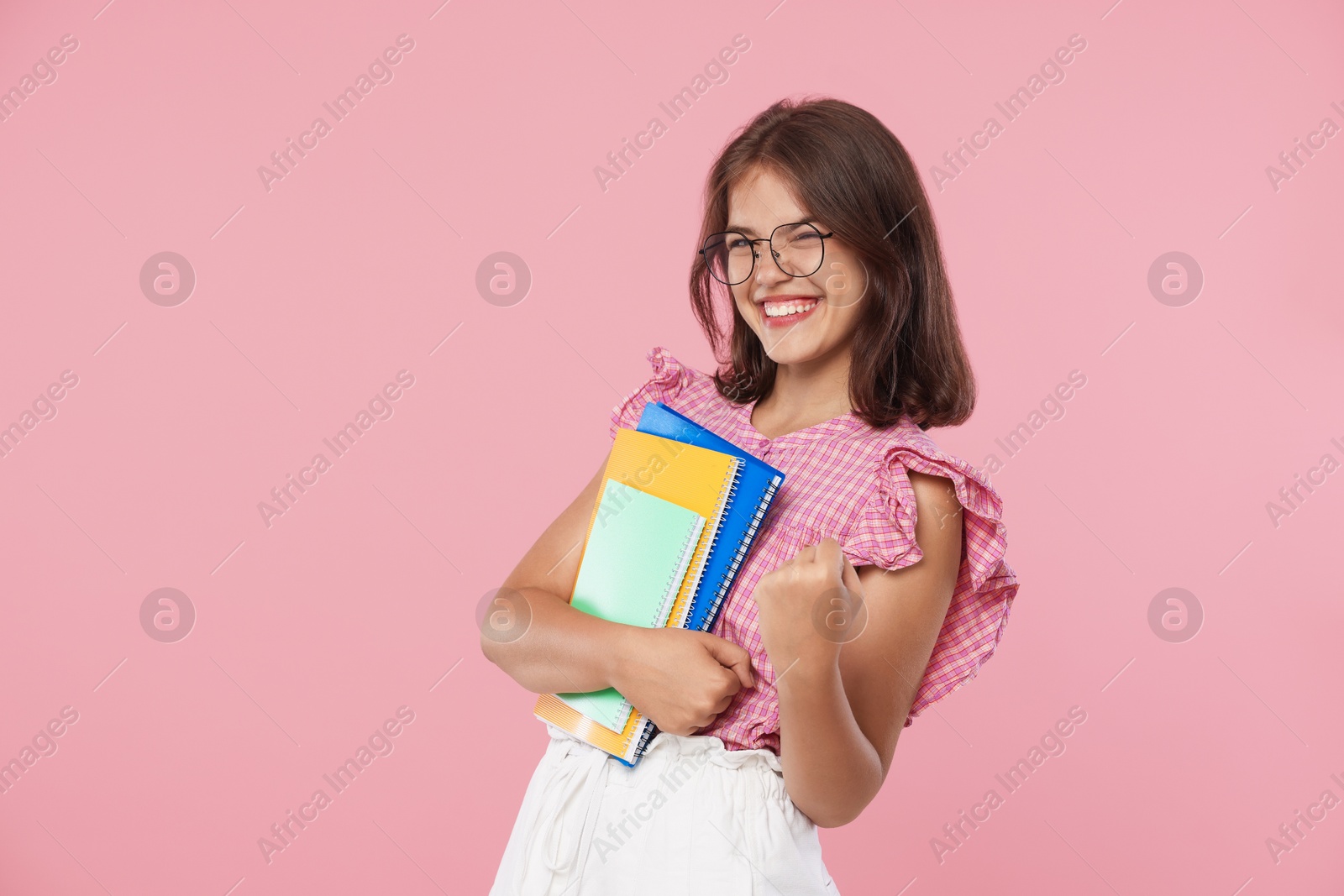 Student feeling happy about her good exam result on pink background Photo of Student feeling happy about her good exam result on pink background
