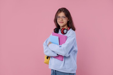 Photo of Student with notebooks and headphones before exam on pink background