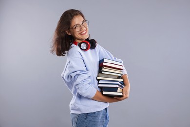 Photo of Student with stack of books feeling happy about her good exam result on gray background