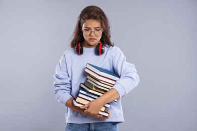 Photo of Student with stack of books worried about her exam result on gray background