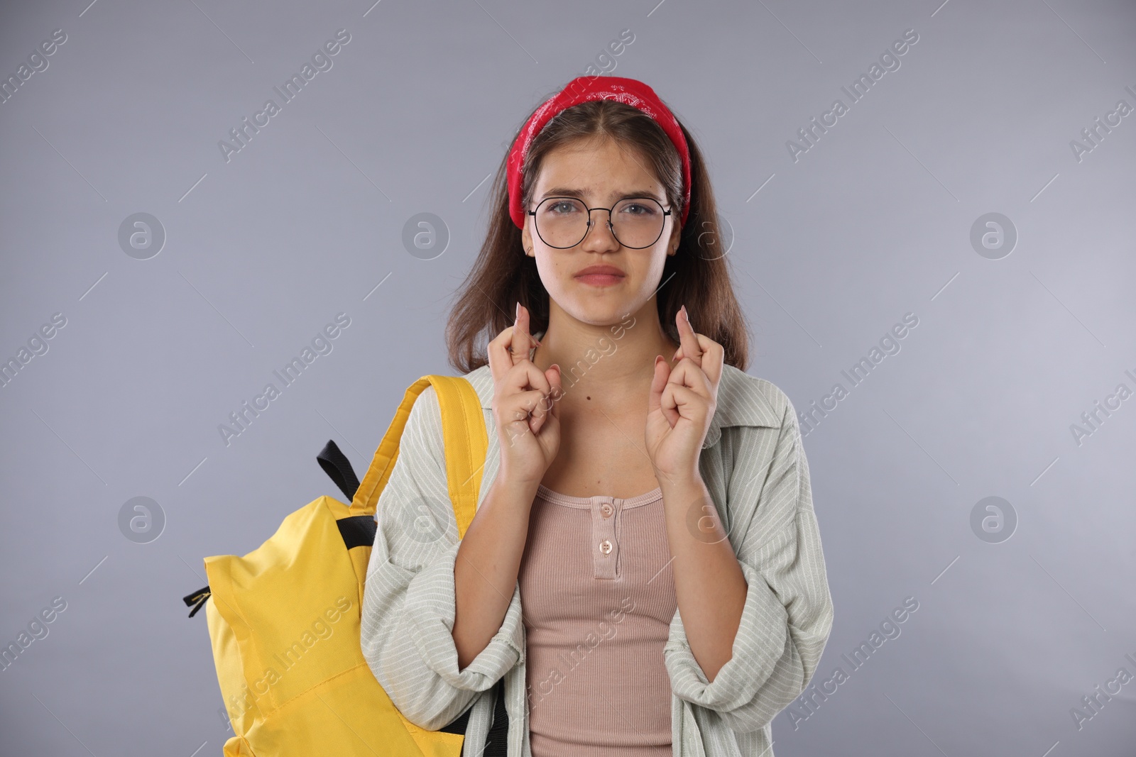 Student crossing fingers on gray background. Hope for good exam result Photo of Student crossing fingers on gray background. Hope for good exam result
