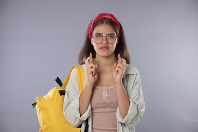 Photo of Student crossing fingers on gray background. Hope for good exam result
