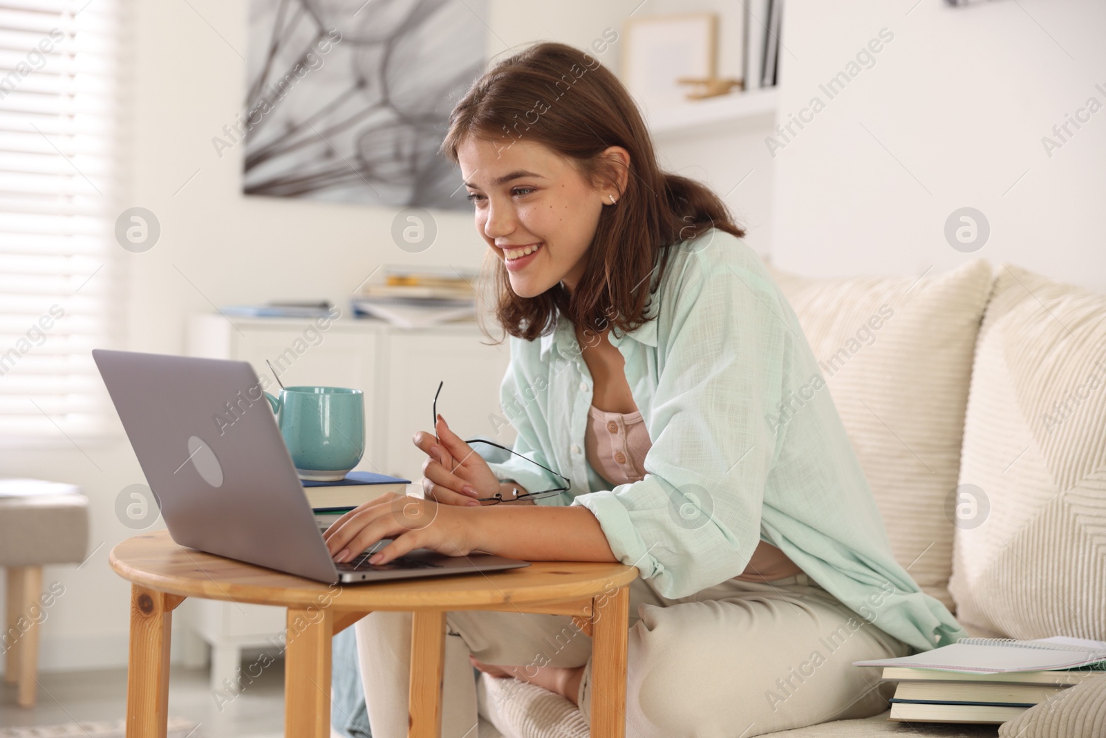 Student feeling happy about her good exam result at wooden table with laptop indoors Photo of Student feeling happy about her good exam result at wooden table with laptop indoors