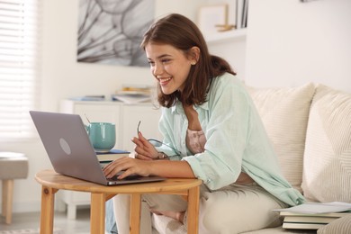 Photo of Student feeling happy about her good exam result at wooden table with laptop indoors