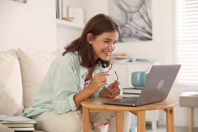 Photo of Student feeling happy about her good exam result at wooden table with laptop indoors