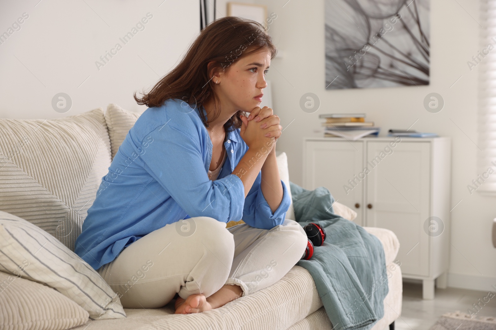 Student praying for good exam result on sofa indoors Photo of Student praying for good exam result on sofa indoors