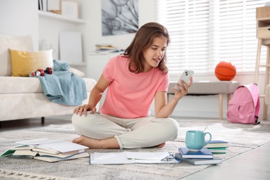 Photo of Student with smartphone feeling happy about her good exam result at home