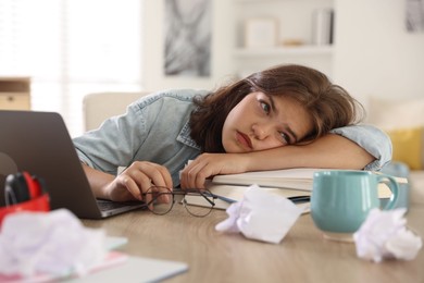 Photo of Tired student preparing for exam at table indoors