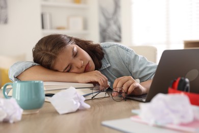 Photo of Tired student preparing for exam at table indoors