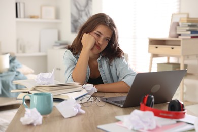 Photo of Tired student preparing for exam at table indoors
