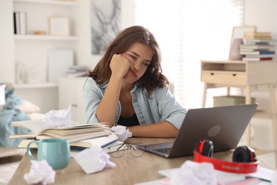 Photo of Tired student preparing for exam at table indoors