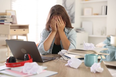 Photo of Tired student preparing for exam at table indoors