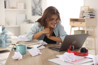 Photo of Student feeling happy about her good exam result at table with laptop indoors