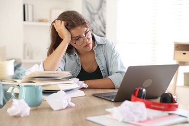 Photo of Tired student preparing for exam at table indoors