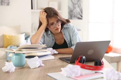 Photo of Tired student preparing for exam at table indoors