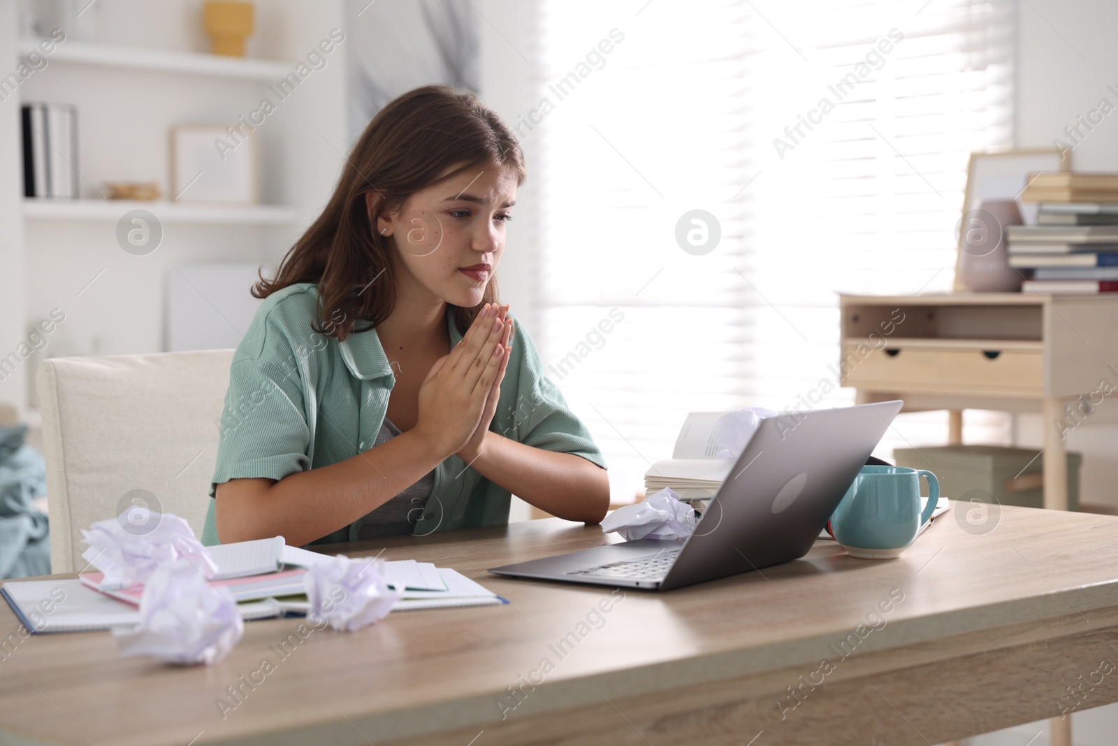 Student praying for good exam result at table indoors Photo of Student praying for good exam result at table indoors