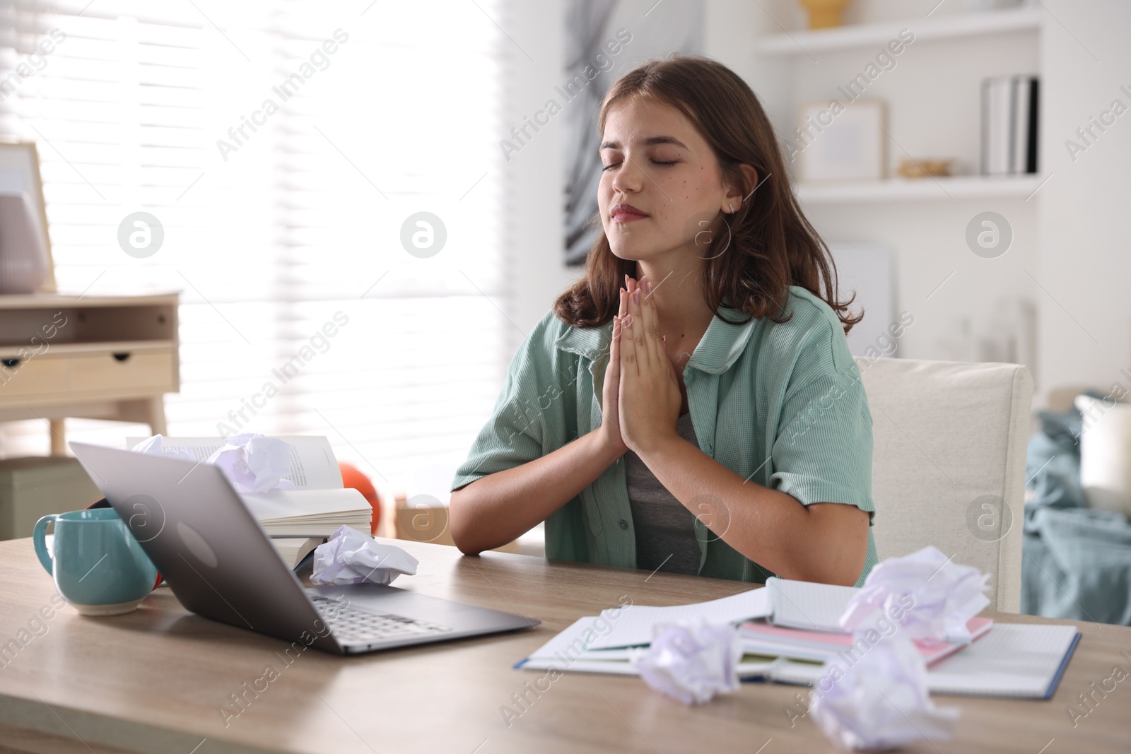 Student praying for good exam result at table indoors Photo of Student praying for good exam result at table indoors
