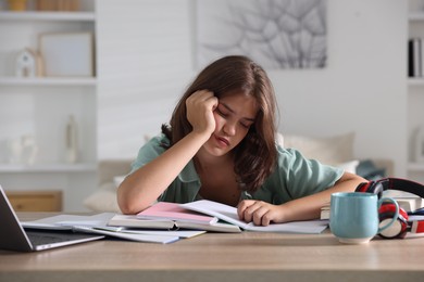Photo of Tired student preparing for exam at table indoors