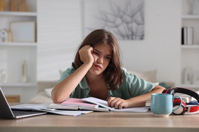 Photo of Tired student preparing for exam at table indoors