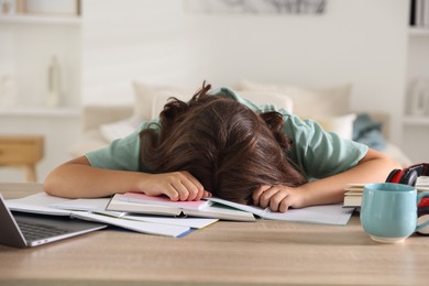 Photo of Tired student preparing for exam at table indoors