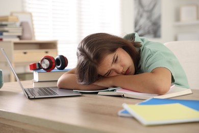 Photo of Tired student preparing for exam at table indoors