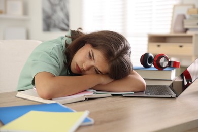 Photo of Tired student preparing for exam at table indoors