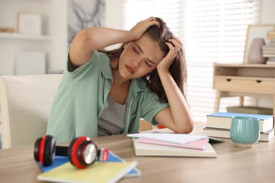 Photo of Tired student preparing for exam at table indoors