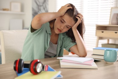 Photo of Tired student preparing for exam at table indoors