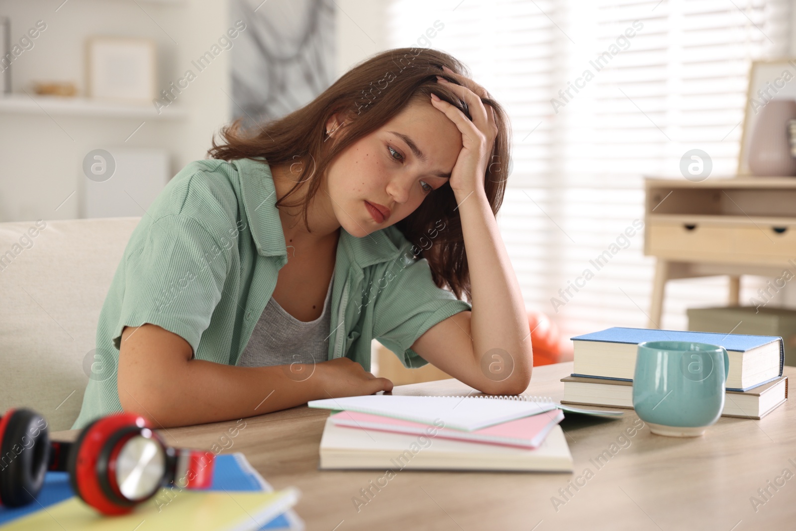 Tired student preparing for exam at table indoors Photo of Tired student preparing for exam at table indoors