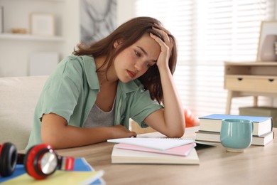 Photo of Tired student preparing for exam at table indoors