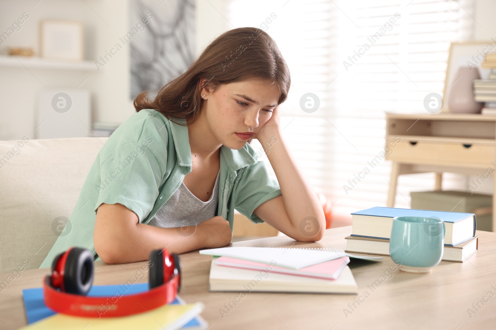 Tired student preparing for exam at table indoors Photo of Tired student preparing for exam at table indoors
