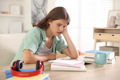 Photo of Tired student preparing for exam at table indoors