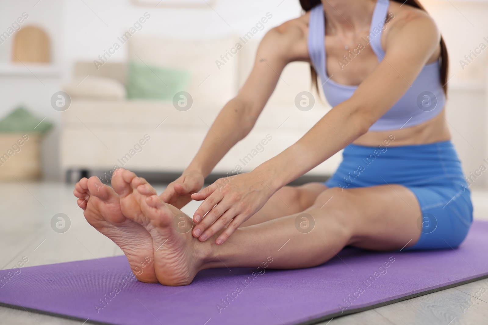 Woman in sportswear stretching on mat at home, closeup Photo of Woman in sportswear stretching on mat at home, closeup