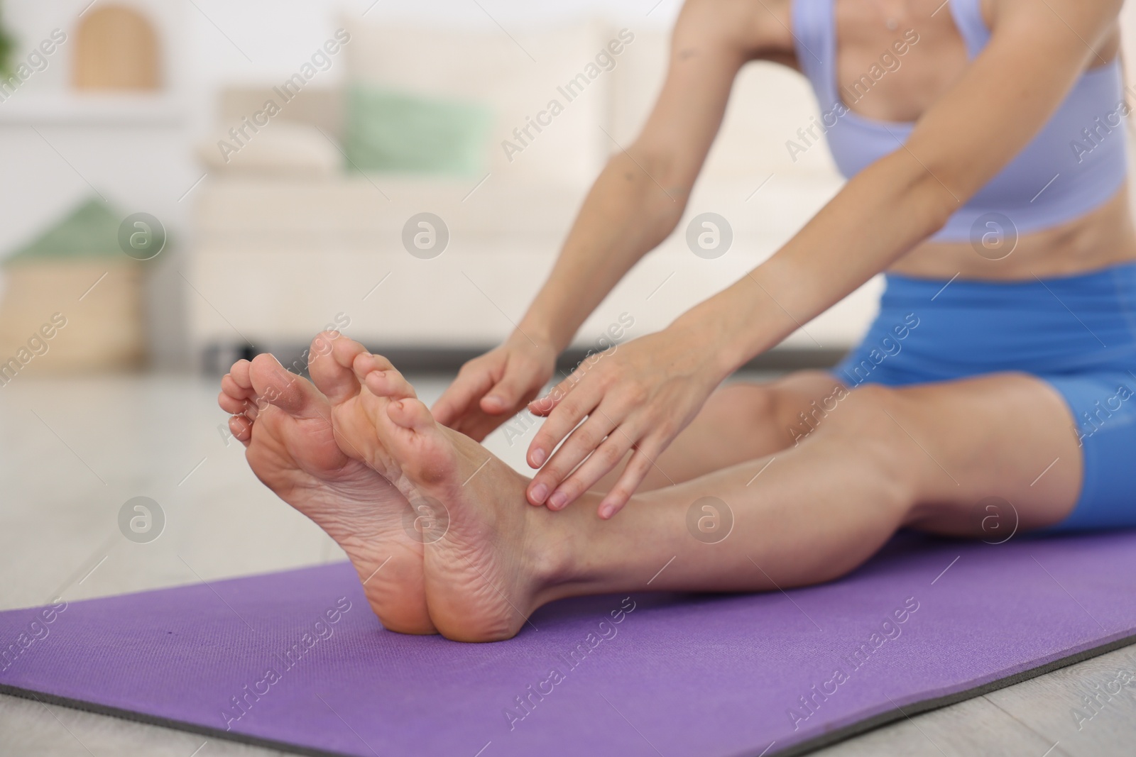 Woman in sportswear stretching on mat at home, closeup Photo of Woman in sportswear stretching on mat at home, closeup
