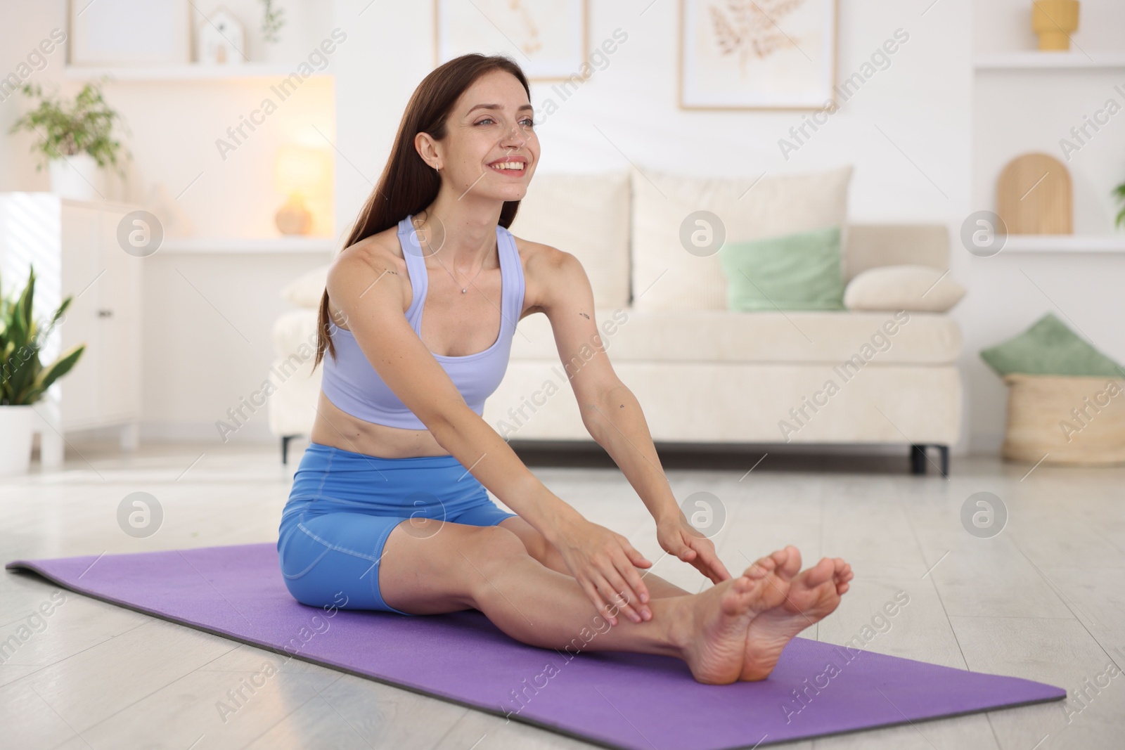 Smiling woman in sportswear stretching on mat at home Photo of Smiling woman in sportswear stretching on mat at home